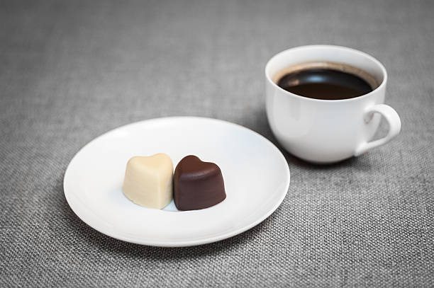 istock Cup of coffee and two heart-shaped chocolates on the plate 578087918