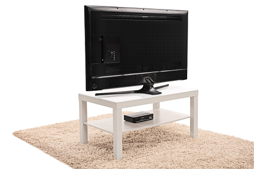 Rear view shot of a modern black flat screen TV on a white wooden TV unit isolated on white background