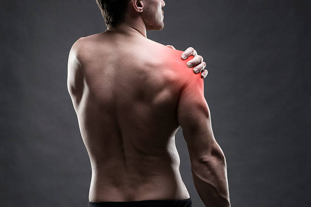 Pain in the shoulder. Muscular male body. Pain in the shoulder. Muscular male body. Handsome bodybuilder posing on gray background with red dot shoulder stock pictures, royalty-free photos & images