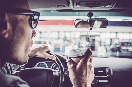 Man driving his Car and drinking take away coffee
