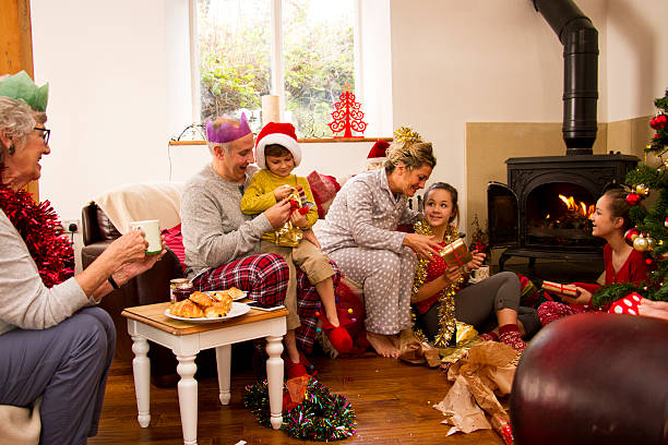 Family enjoying Christmas morning together. The children are opening presents with their parents and the grandmother is watching.