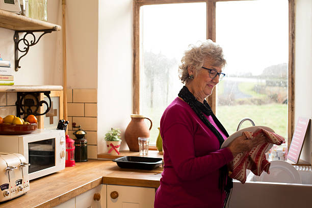 Grandma Drying Dishes Shot of Grandma drying dishes in the kitchen independent stock pictures, royalty-free photos & images