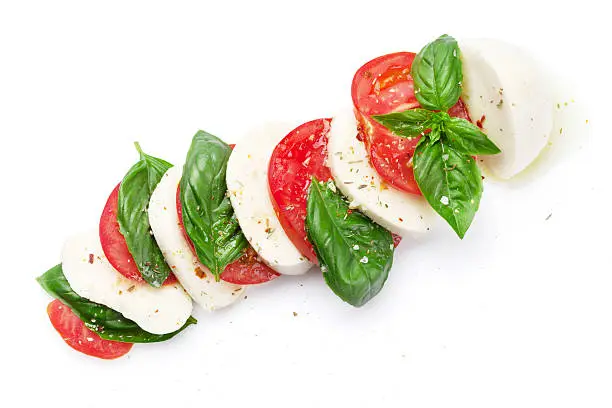 Caprese salad. Mozzarella cheese, tomatoes and basil herb leaves. Isolated on white background. Top view