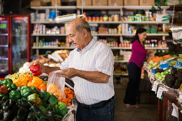 bell'uomo anziano che compra peperoni al supermercato - senior adult aging process supermarket shopping foto e immagini stock