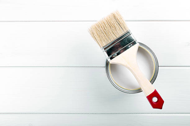paint can with paintbrush on white wooden background