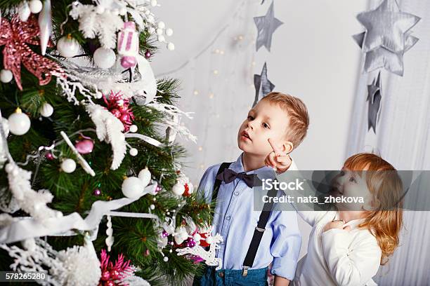 Two Little Kids Decorating Christmas Tree With Toys Flowers And Stock Photo - Download Image Now