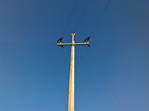 Energy Pole Bend. Concrete pillar, electric wires. Power Supply, curve of energy line. Blue sky.