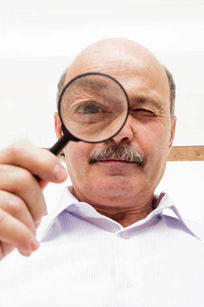 istock elderly man looks at something through magnifying glass. 578273346