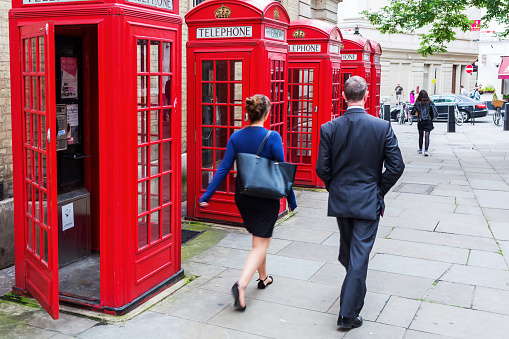 London, UK - June 16, 2016: unidentified people walking along traditional red phone boxes at Covent Garden. the red phone boxes are iconic symbols of London