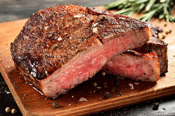 mittleres seltenes ribeye-steak auf holzbrett, ausgewählter fokus - steak stock-fotos und bilder