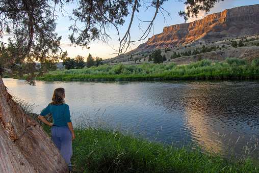Woman viewing the light across the John Day River. Northern Oregon, Pacific Northwest.
