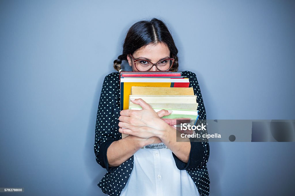 Shy girl Nerd  girl holding some books , on gray background,hiding Book Stock Photo