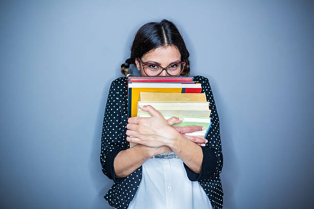 Shy girl Nerd  girl holding some books , on gray background,hiding nerd teenager stock pictures, royalty-free photos & images