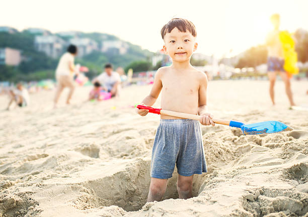 Child's Hand Filling Yellow Shovel with Sand at the Beach
