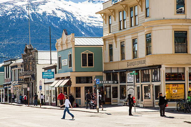Skagway, AK, USA, May 11, 2016.  Shoppers and photographers visit Broadway Street, which features false-front shops and restaurants, wooden sidewalks and restored buildings. 