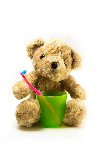 istock Teddy bear with a kid toothbrush and plastic glass 578292276