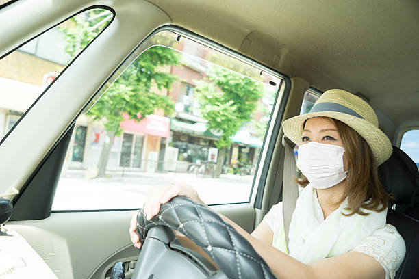 joyeuse japonaise conduisant une voiture portant un masque antipollution - antipollution photos et images de collection