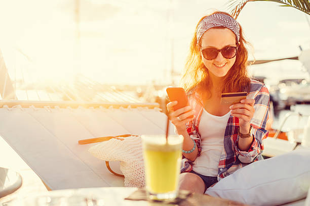 Woman using credit card on a vacation Woman in a hammock using credit card for online shopping  +++++ Note for the inspector : Credit card is fake +++++ spending money stock pictures, royalty-free photos & images