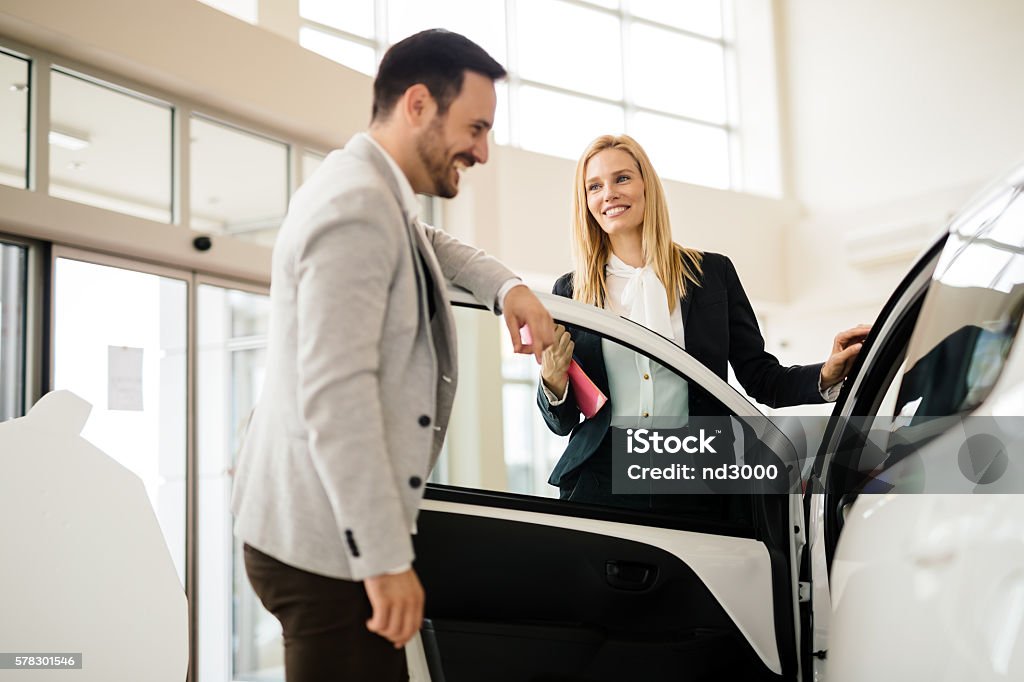 Salesperson showing vehicle to potential customer Salesperson showing vehicle to potential customer in dealership Car Salesperson Stock Photo