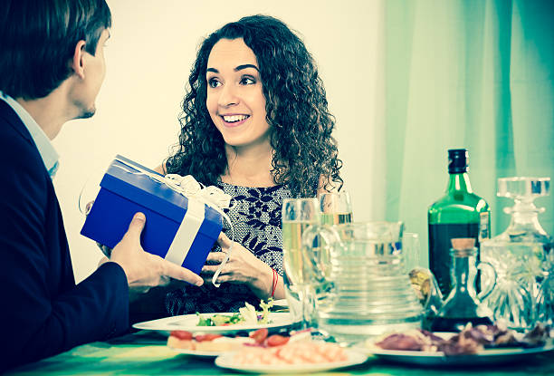 Man giving present to woman Man giving present to happy woman during romantic dinner in home wonderingly stock pictures, royalty-free photos & images