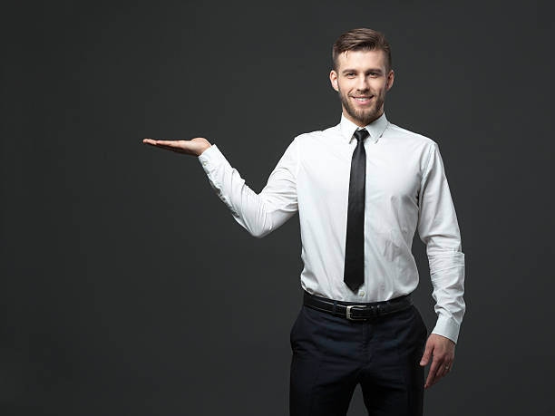 istock Young businessman holding his arm up presenting copyspace. 578308744