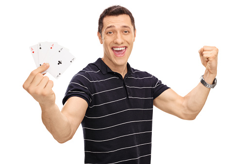 Lucky young man holding four aces in his hand and gesturing happiness isolated on white background