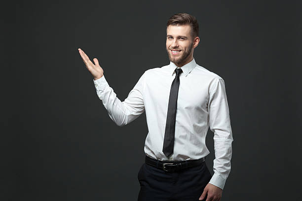 istock Young businessman holding his arm up presenting copyspace. 578308786