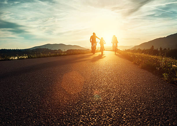 Сyclists family traveling on the road at sunset Сyclists family traveling on the road at sunset weekend trip stock pictures, royalty-free photos & images