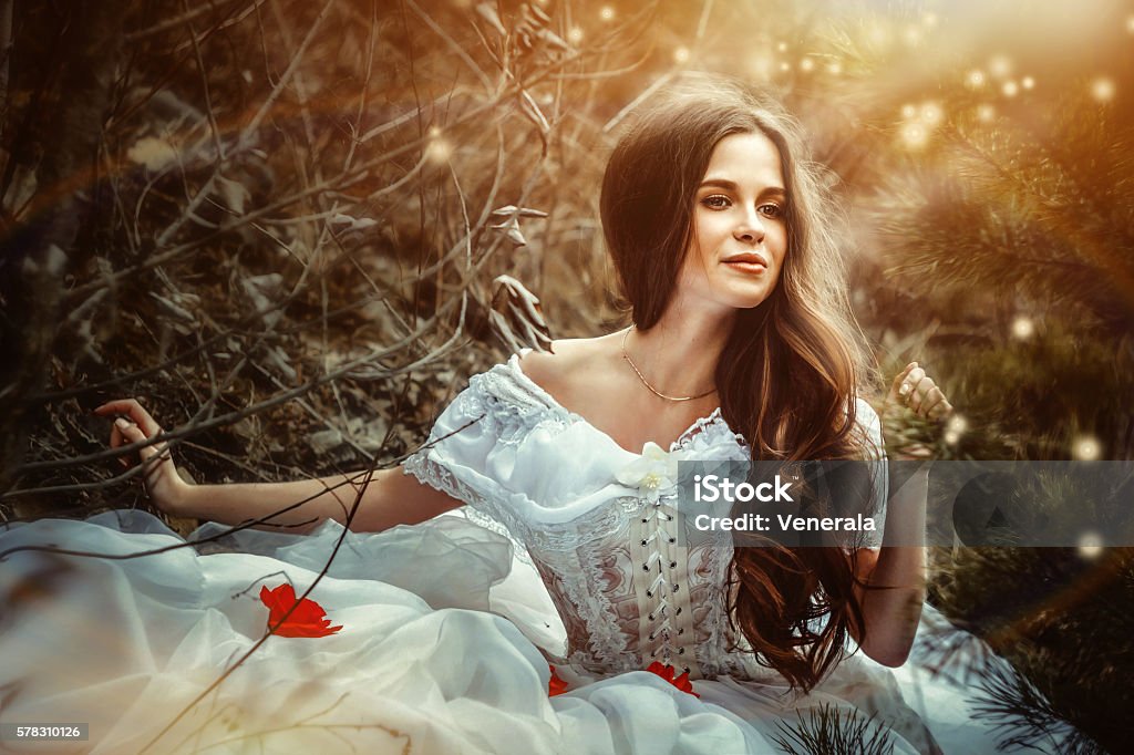 girl in a dress sitting in the woods girl in white dress sitting in forest smiling Adult Stock Photo