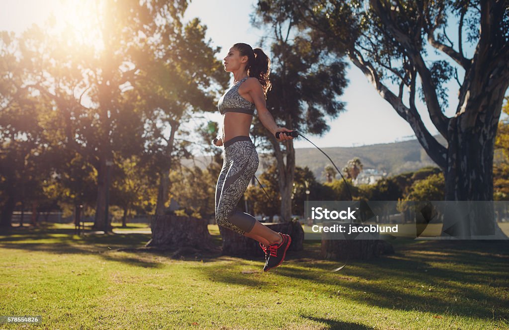 Fit young woman skipping with a jump rope Full length portrait of fit young woman skipping with a jump rope in the park on a summer day. Jumping Rope Stock Photo