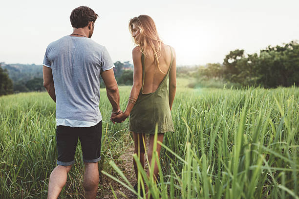 istock Young couple walking through grassy road 578556402