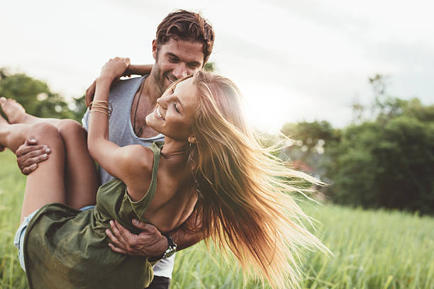 kobieta prowadzona przez swojego chłopaka w polu - couple fun outdoors day zdjęcia i obrazy z banku zdjęć