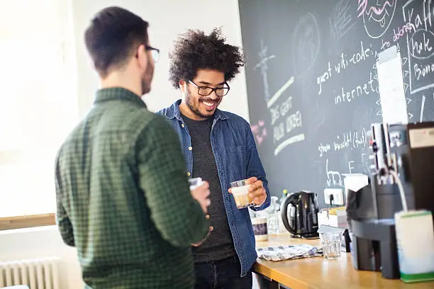Young african man with colleague having coffee during break in startup office