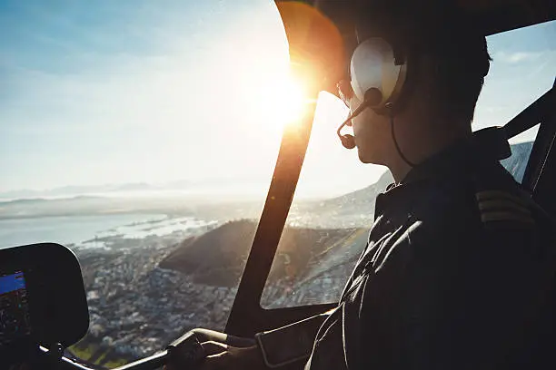 Close up of a helicopter pilot flying aircraft over a city on a sunny day