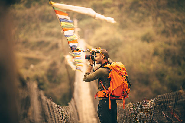 Making memories of beautiful Nepal Photo of a hiker making photographs of the beautiful view over the bridge in Annapurna Range on Himalayas, Nepal nature and landscapes camera stock pictures, royalty-free photos & images