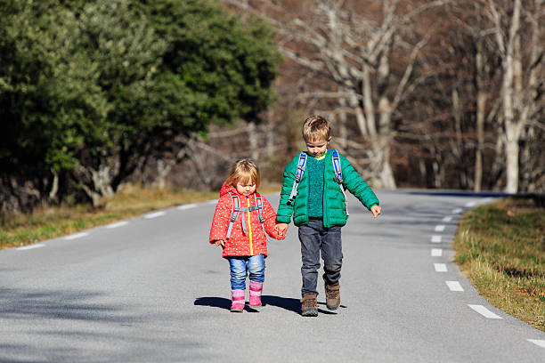istock brother and sister with backpacks walking on the road 578565384