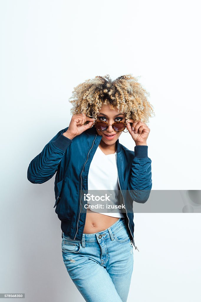Portrait of cool afro american young woman Portrait of sensual afro american young woman in fashionable outfit wearing sunglasses, smiling at camera.  Adult Stock Photo