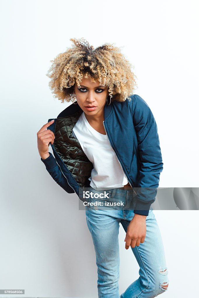 Portrait of afro american young woman Portrait of afro american young woman wearing bomber jacket, denim trausers and sunglasses, looking at camera. Adult Stock Photo