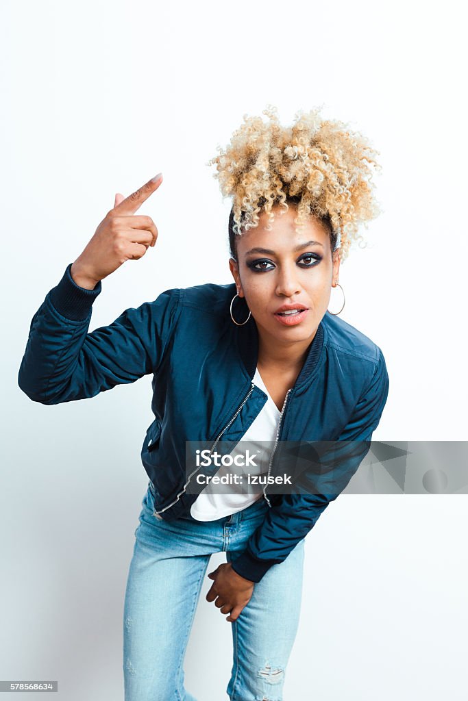 Portrait of cool afro american young woman Portrait of sensual afro american young woman wearing bomber jacket and denim trausers, looking at camera.  Adult Stock Photo