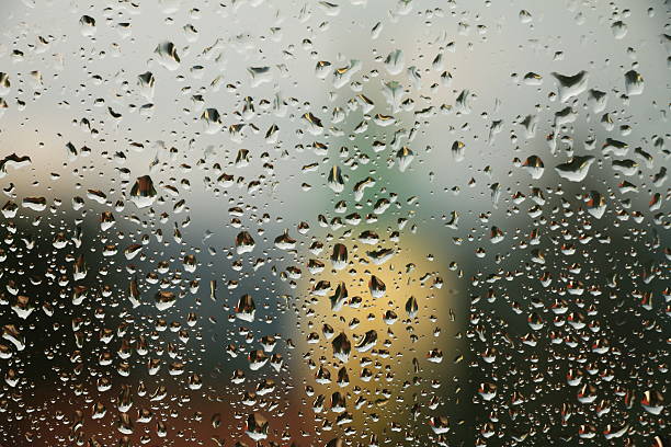 istock Rain drops on window with house and church in background 578570618