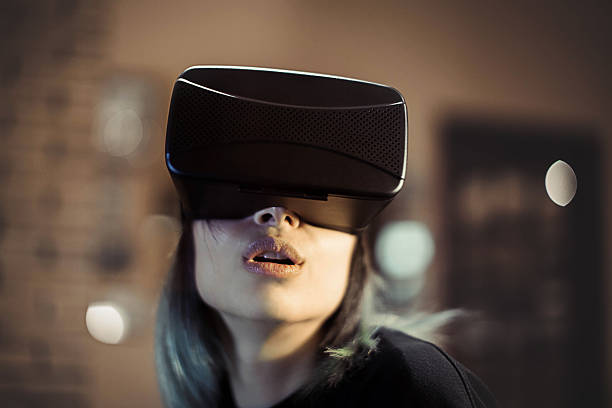 Stock photo of a young woman looks fascinated into Virtual Reality Headset