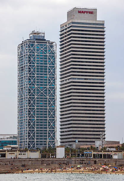 Barcelona, Spain - July 7, 2016: Skyscrapers Torre Mapfre in the Olympic Port. It is named after its owner, Mapfre, an insurance company. This tower holds the title for highest helipad in Spain at 505 feet above ground. People are on the beach.