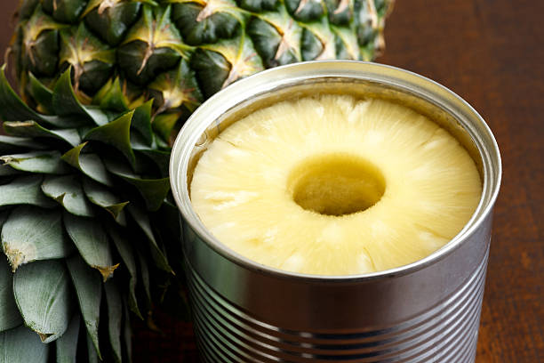 istock Pineapple rings in tin on dark wood next to pineapple. 578575736