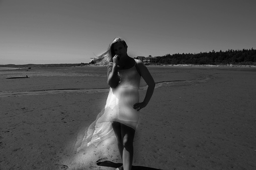 creative portrait of young woman wearing dress on beach