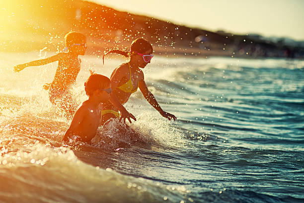 Three kids swimming and having fun at sea at sunset