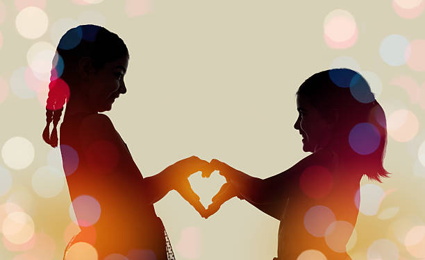 istock Silhouette of two girls making heart 578580418