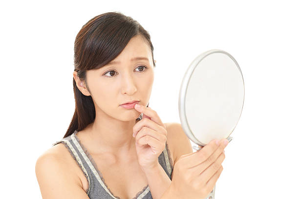 istock Asian woman looking at her face in mirror 578581400