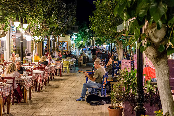 Night street with tavernas full of tourists and street musicians Paleochora, Crete, Greece - June 29, 2016: Night street with tavernas full of tourists and street musicians at Paleochora town in west part of Crete island. herakleion photos stock pictures, royalty-free photos & images