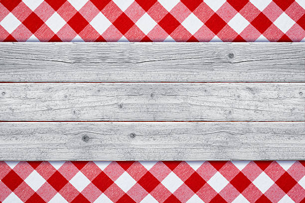 White rustic wood resting upon a traditional picnic red and white gingham tablecloth