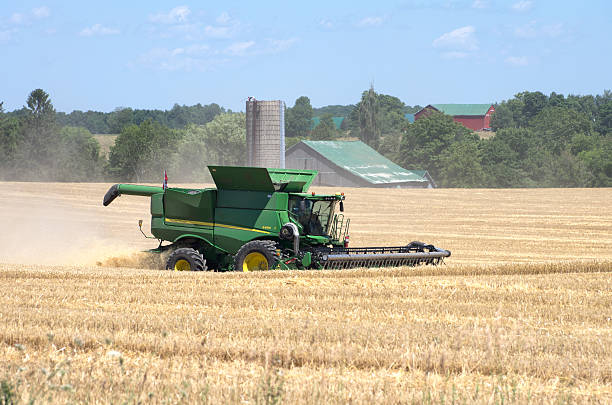 Harriston, Ontario, Canada - July 22, 2016: A large John Deere combine harvesting winter wheat in the midst of the summer harvest in Southwestern Ontario.
